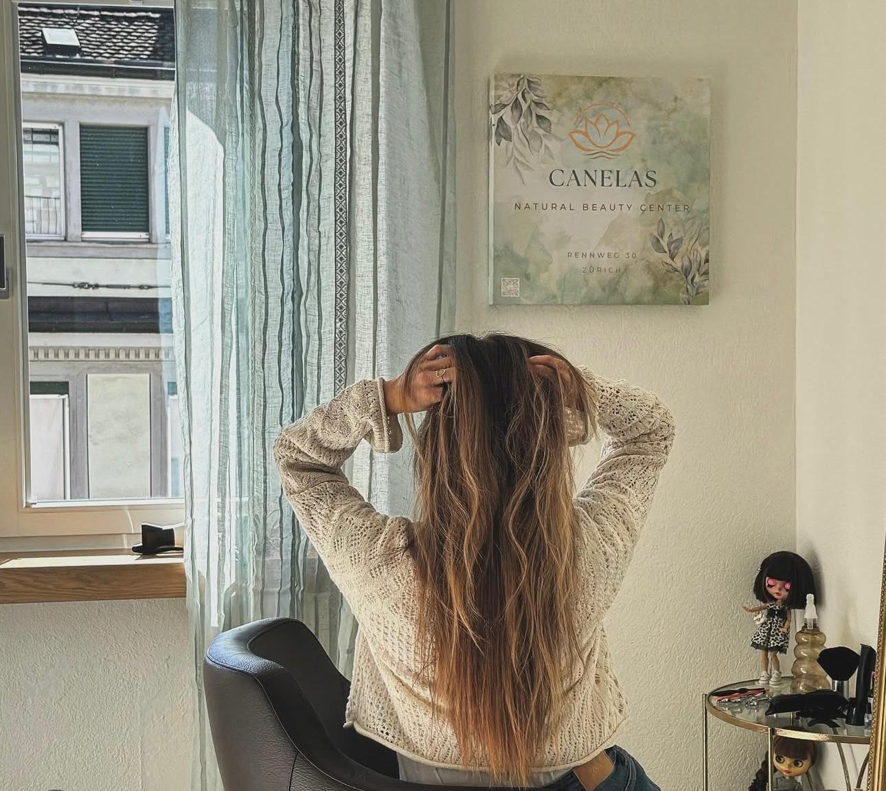 Kundin mit langem Balayage-Haar vor der Canelas-Wandtafel am Stylingplatz, Rennweg 30, Zürich