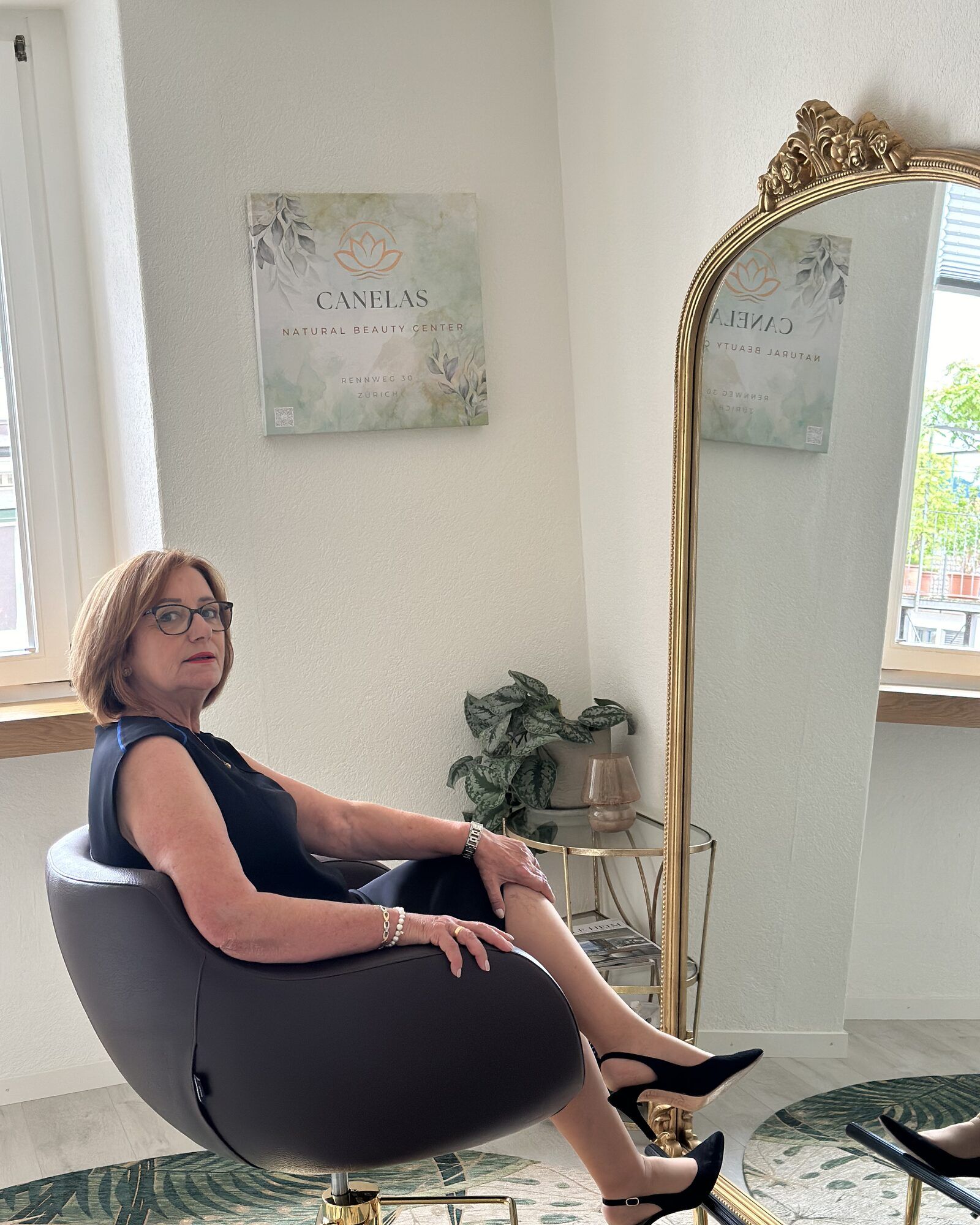 Frau mit rotbraunem Bob sitzt im Frisierstuhl vor dem Wandbild des Canelas Natural Beauty Center
