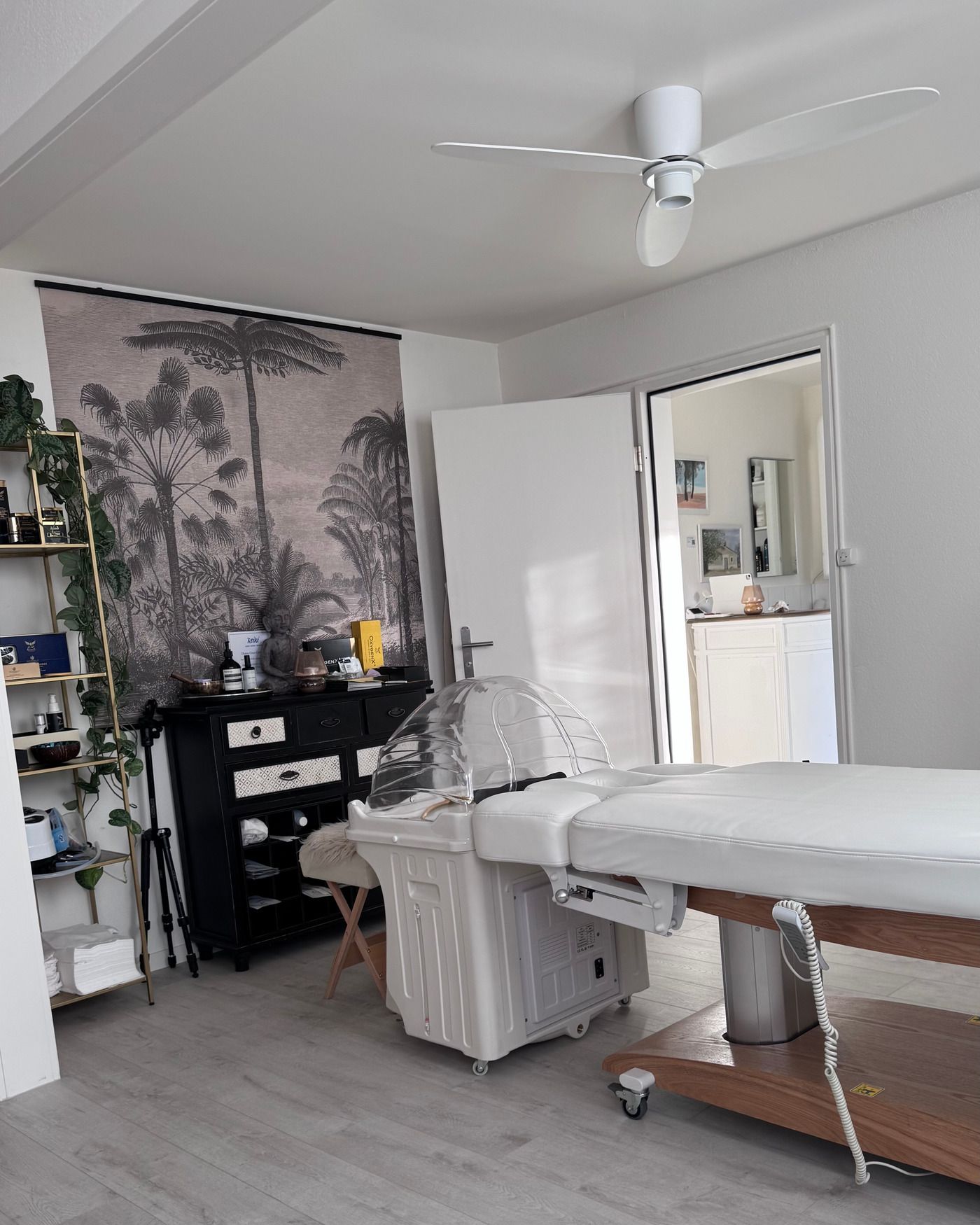 Head-Spa-Station mit transparenter Haube an der weissen Liege, dahinter Palmen-Wandbild und Buddha-Figur